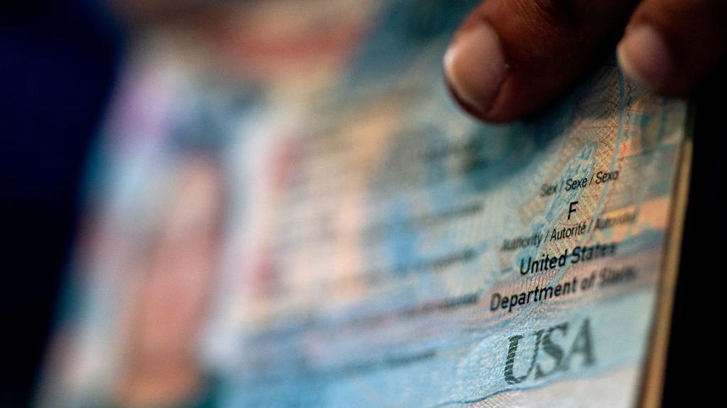 Una persona muestra el marcador de género femenino en su actual pasaporte estadounidense, antes de comenzar el proceso de completar una solicitud de pasaporte con un marcador de género 'X', en su hogar en Alexandria, Virginia, el 11 de abril de 2022. Foto por STEFANI REYNOLDS/AFP a través de Getty Images)