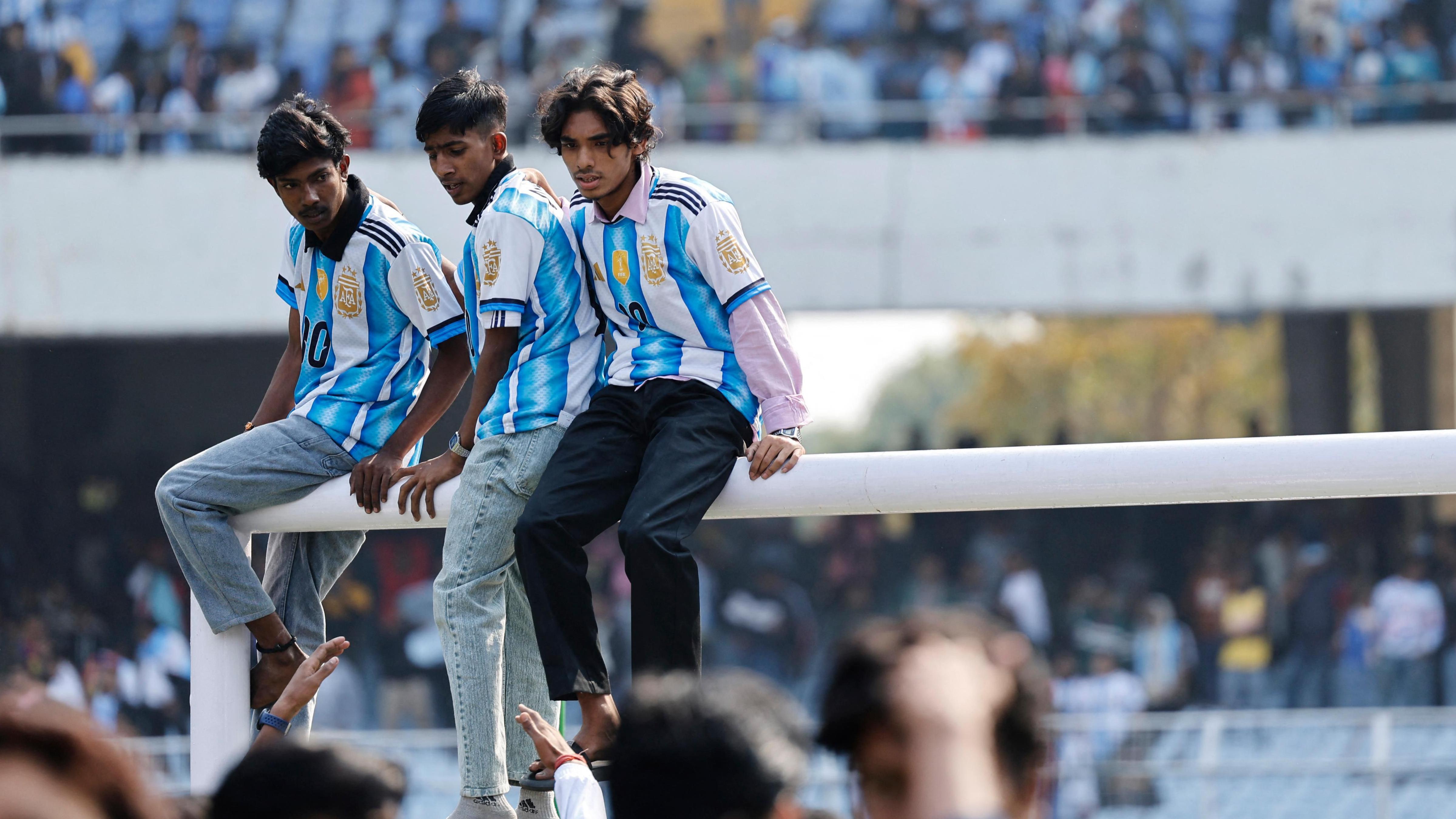 三名男子身穿阿根廷隊的藍白間條衫，坐在球門橫梁上（13/12/2025）
