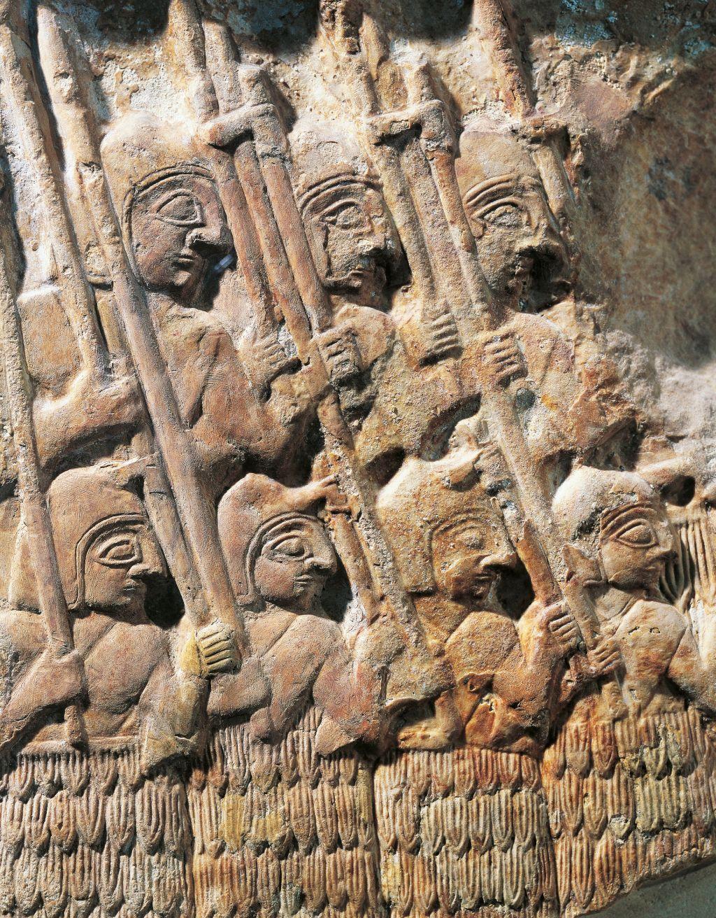 Grabado en piedra caliza mostrando soldados organizados y cargando armas