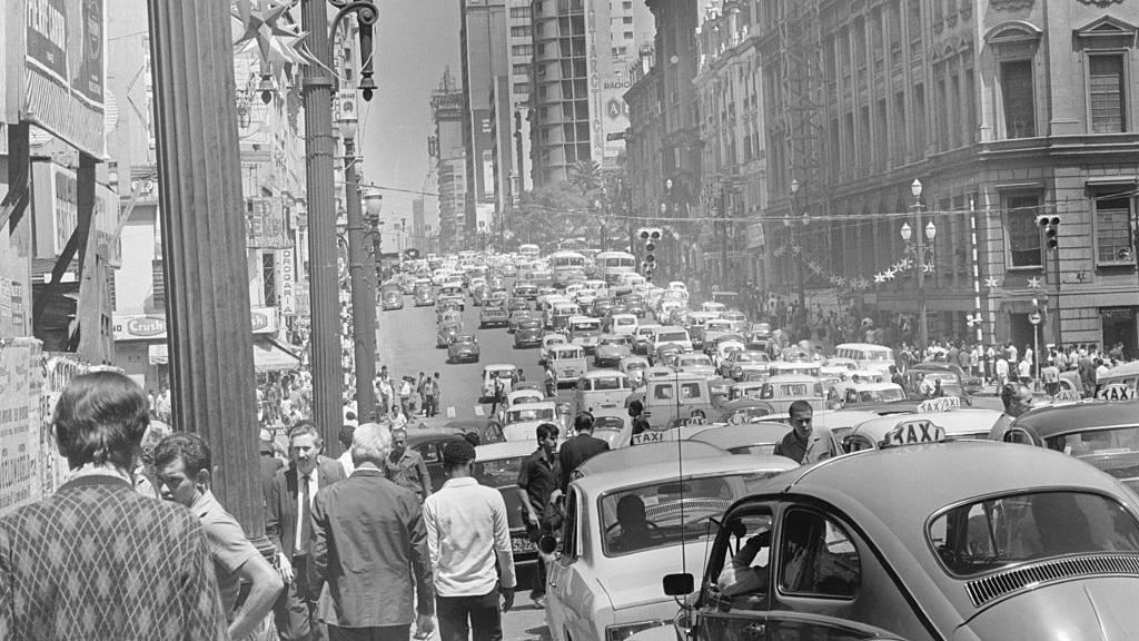 Carros, pedestres e pr&eacute;dios em foto em preto e branco de S&atilde;o Paulo