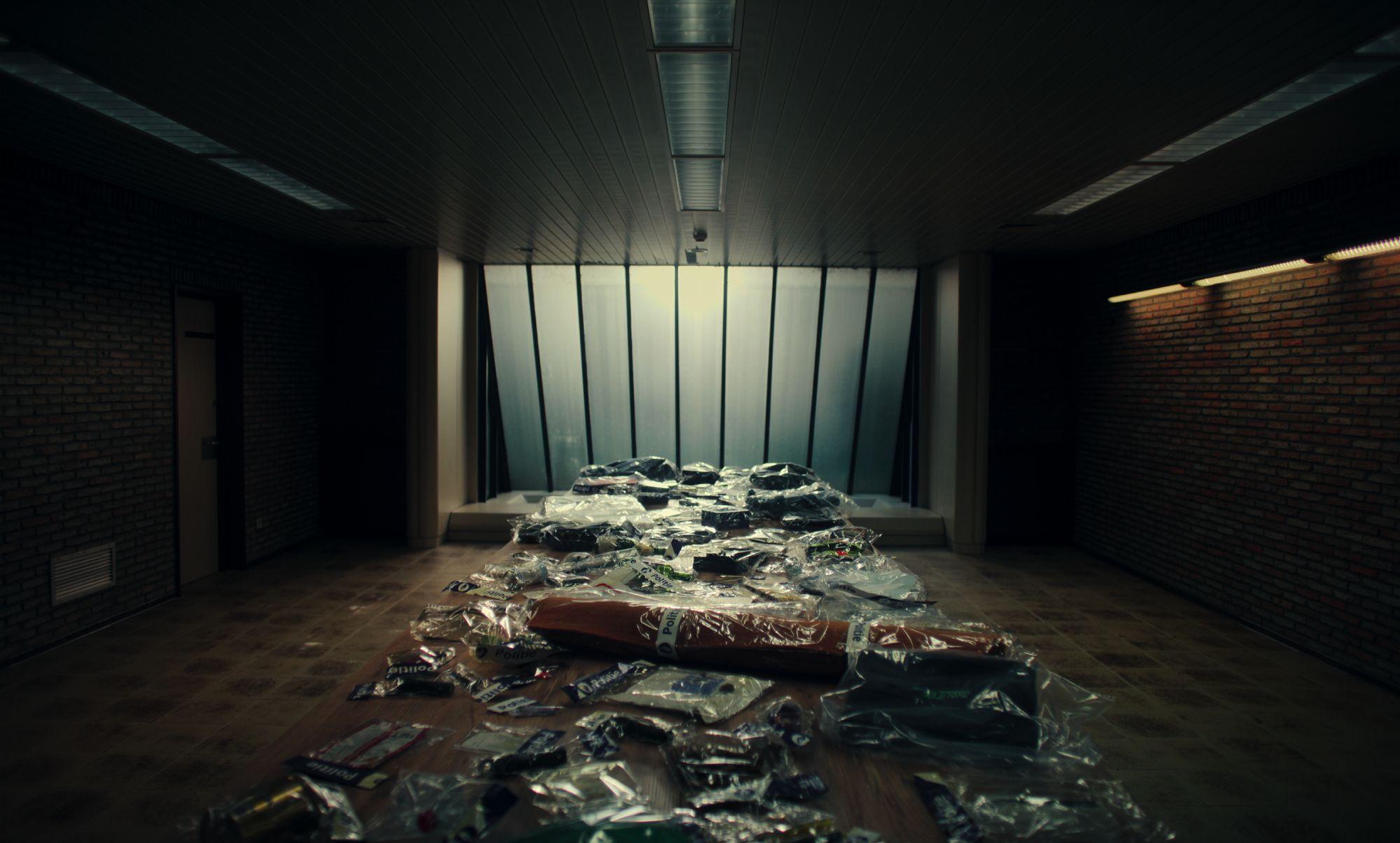 Mesa cubierta con bolsas plásticas que contienen joyas y objetos, en una sala con paredes de ladrillo y gran ventanal al fondo