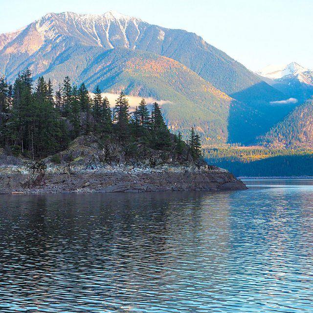 Lago com pinheiros e montanhas ao fundo