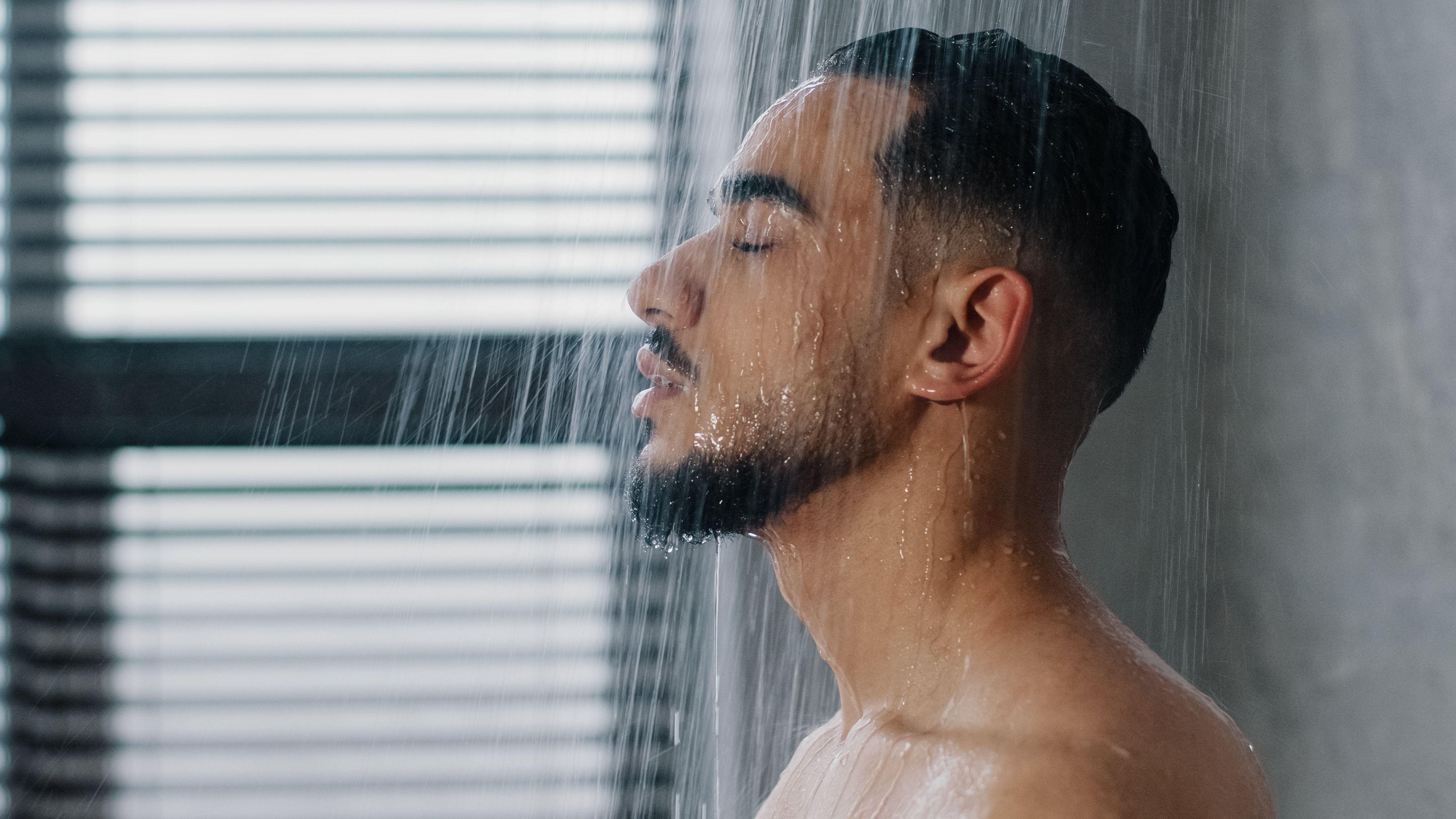 Homem jovem tomando banho de chuveiro