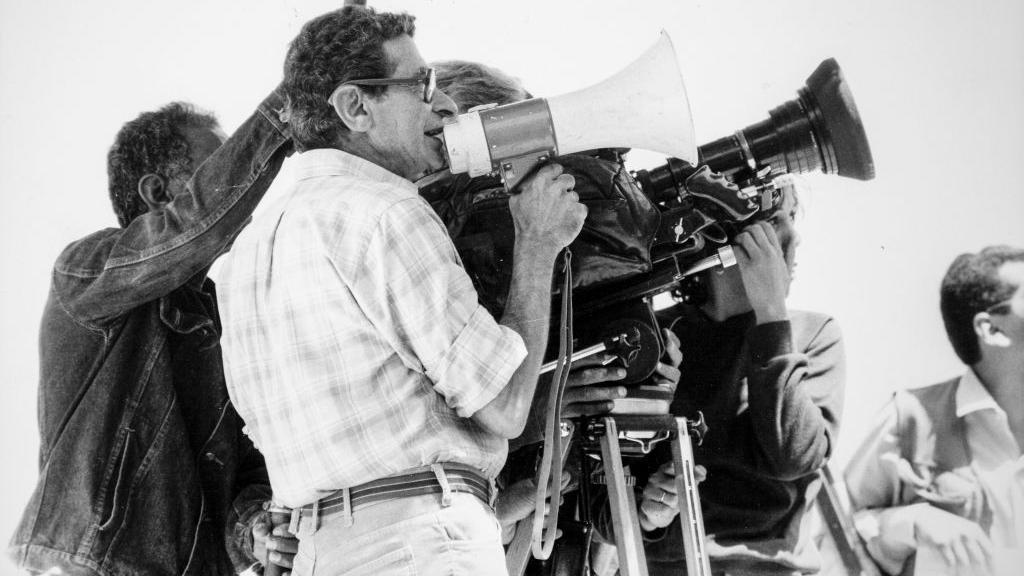 يوسف شاهين يمسك بمكبر صوت أمام الكاميرا - صورة بالأبيضوالأسود