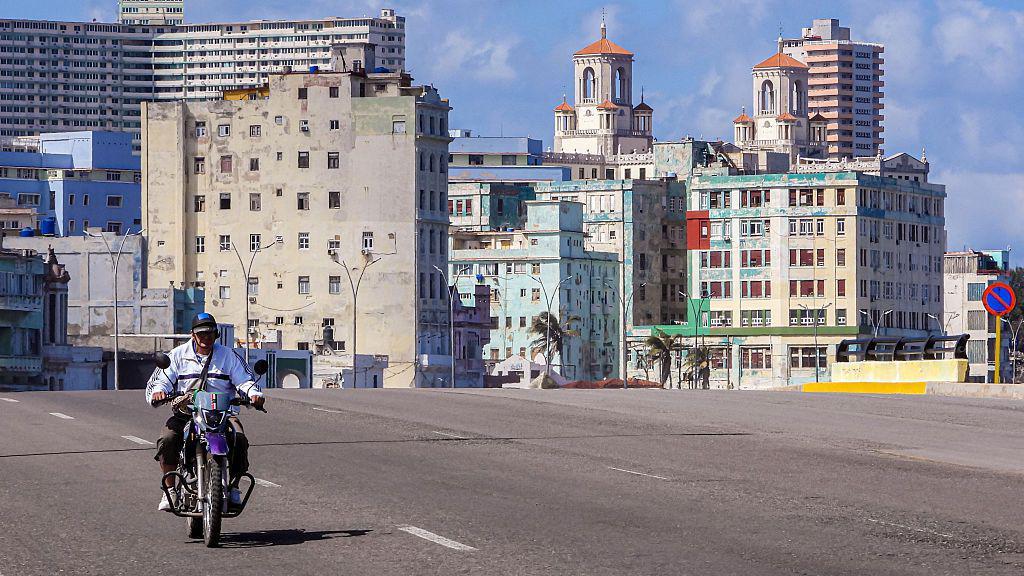 Un hombre con casco en una moto pasa por el malecón de La Habana. Atrás se ven dos de los hoteles más icónicos de la capital cubana.