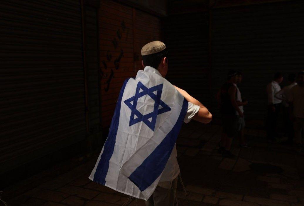 شخص يرتدي العلم الإسرائيلي يدخل باب العامود خلال "مسيرة العلم" الإسرائيلية في البلدة القديمة في القدس.
