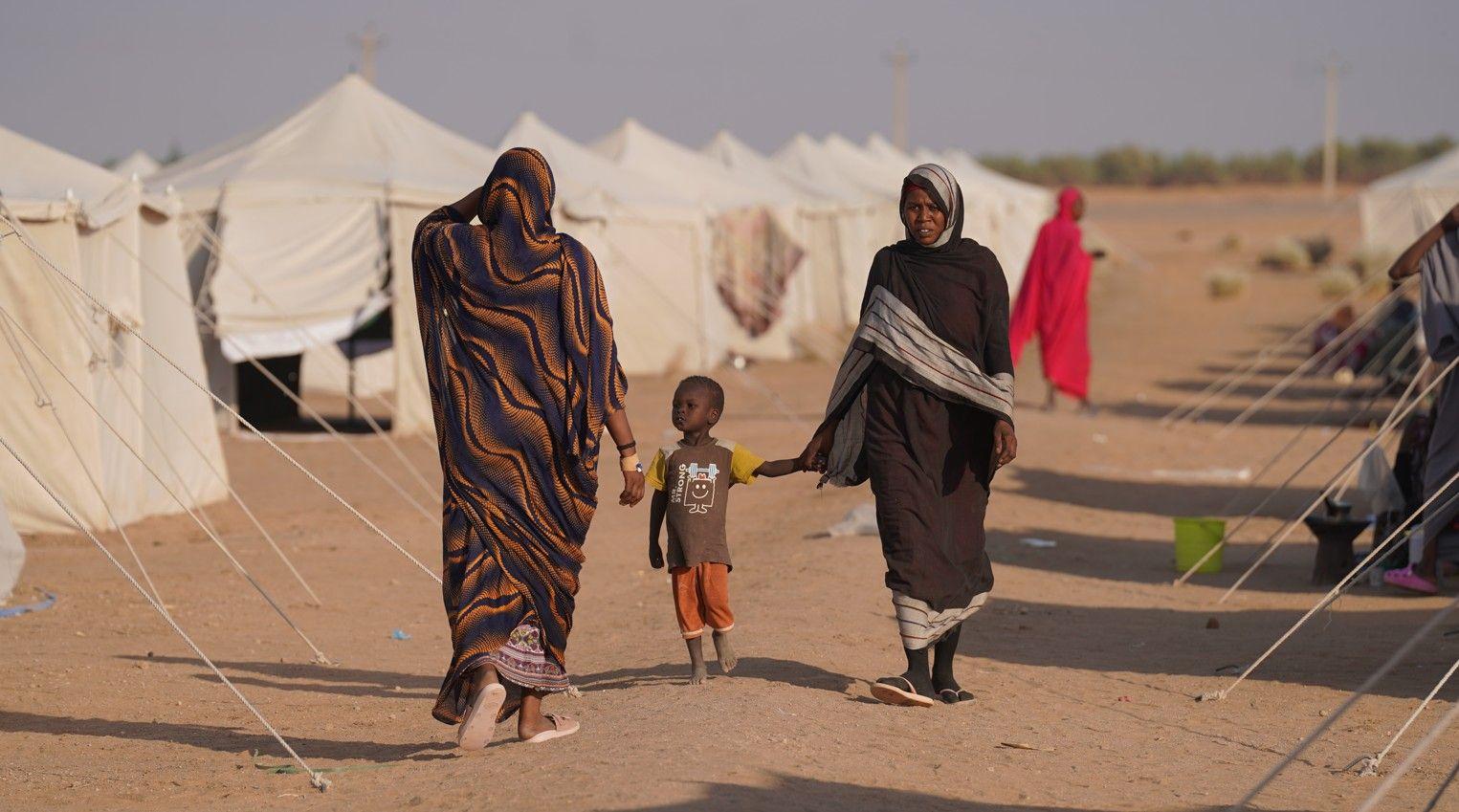 نساء سودانيات يسرن في مخيم
