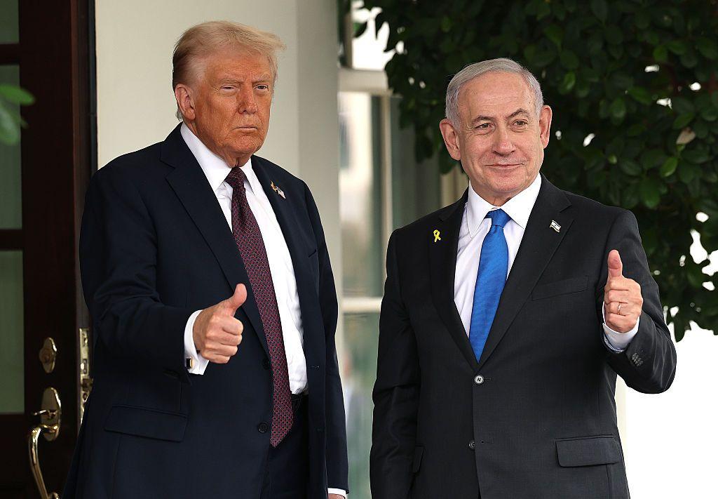 El presidente de Estados Unidos, Donald Trump (izquierda), vestido con traje de chaqueta azul oscuro, camisa blanca y corbata en tonos burdeos. A la derecha, el primer ministro israelí, Benjamin Netanyahu, con traje de chaqueta azul marino oscuro, camisa blanca y corbata azul claro. En las solpas de su chaqueta lleva un pin con la bandera de Israel y otro con un lazo amarillo, que se ha convertido en símbolo de la liberación de los rehenes israelíes a manos de Hamás. Ambos, Trump y Netanyahu, hacen un gesto con su mano de pulgar hacia arriba.