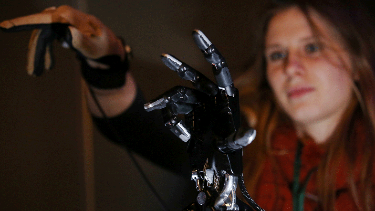 Uma mulher demonstra uma mão robótica.