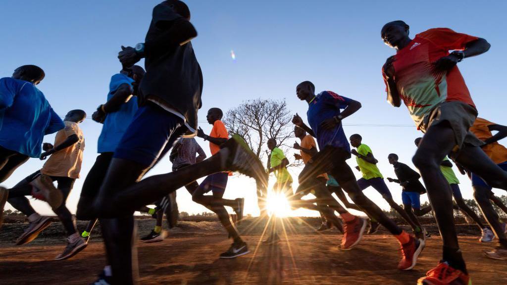 Um grupo de corredores participa de uma sess&atilde;o de treinamento perto do vilarejo queniano de Kapsabet. Eles treinam enquanto o sol nasce ao fundo.