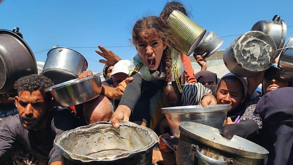 Hombres, mujeres y niños buscan comida en Gaza.