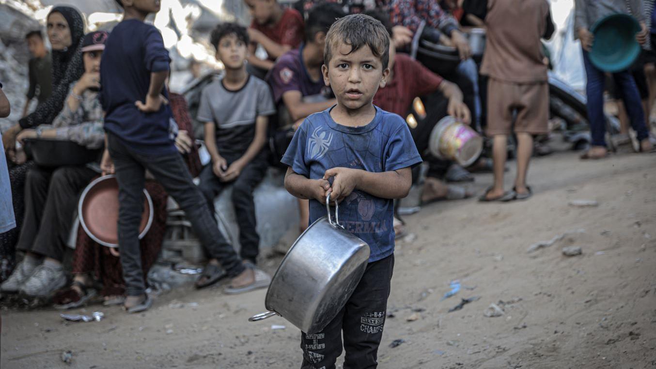 Seorang anak di Gaza antre makanan dengan membawa panci 