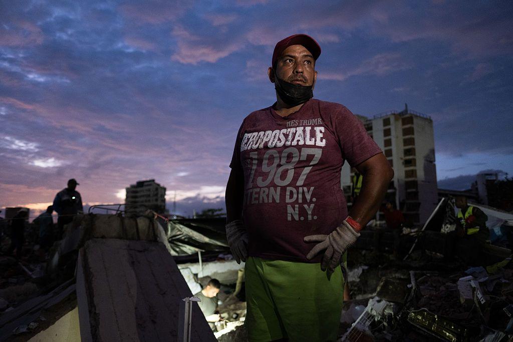 Un hombre, al atardecer, rodeado de edificios destruidos por los terremotos. 