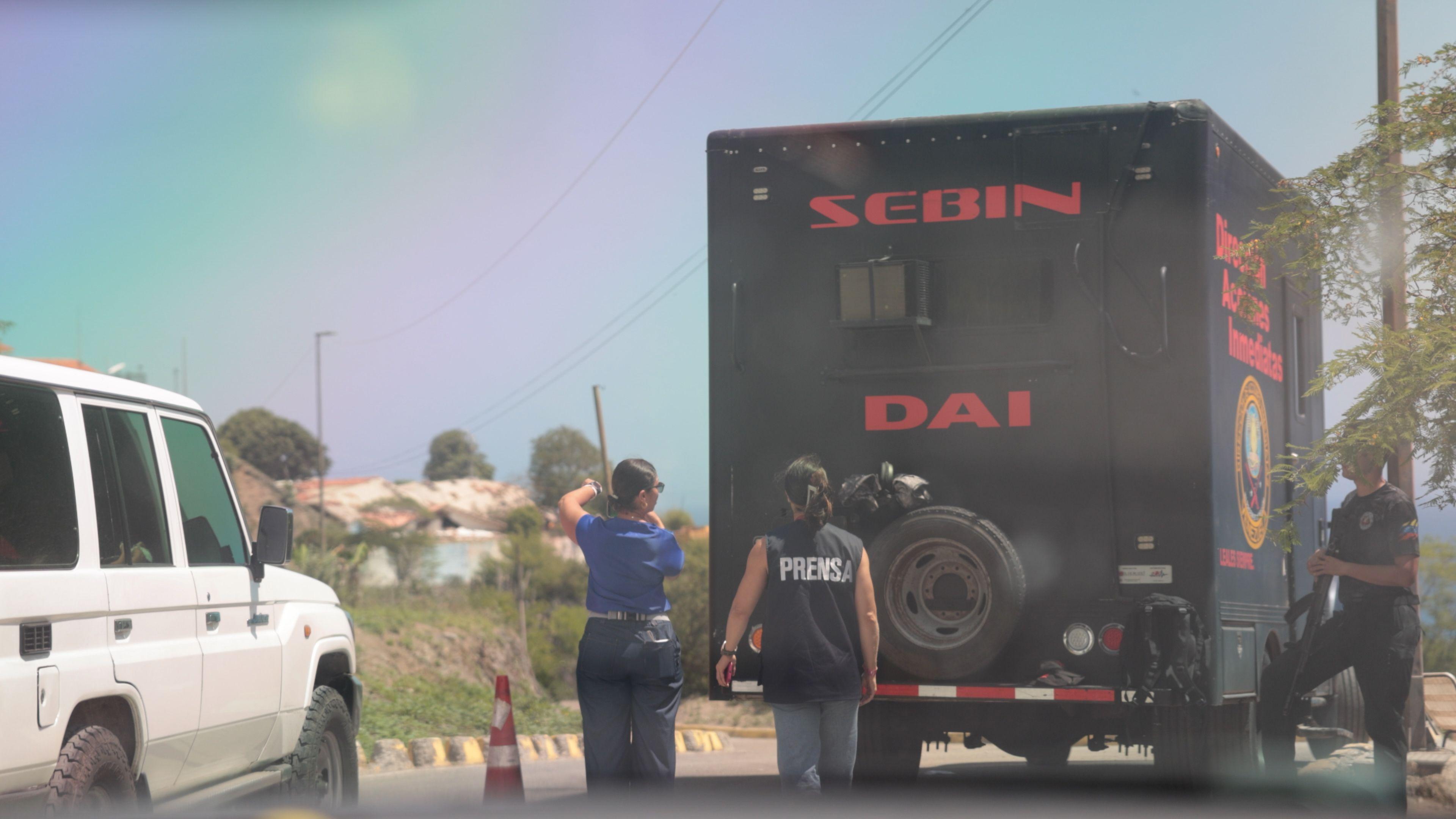 Un camión del Sebin, dos agentes y una periodista con chaleco que dice "prensa" en La Guaira, Venezuela, julio de 2026.