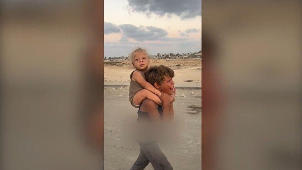 Jadoua camina con su hermanito en los hombros 