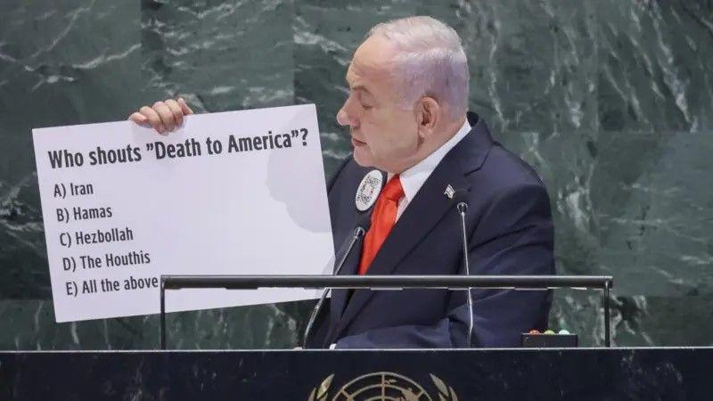 Netanyahu exibindo um cartaz em que pergunta 