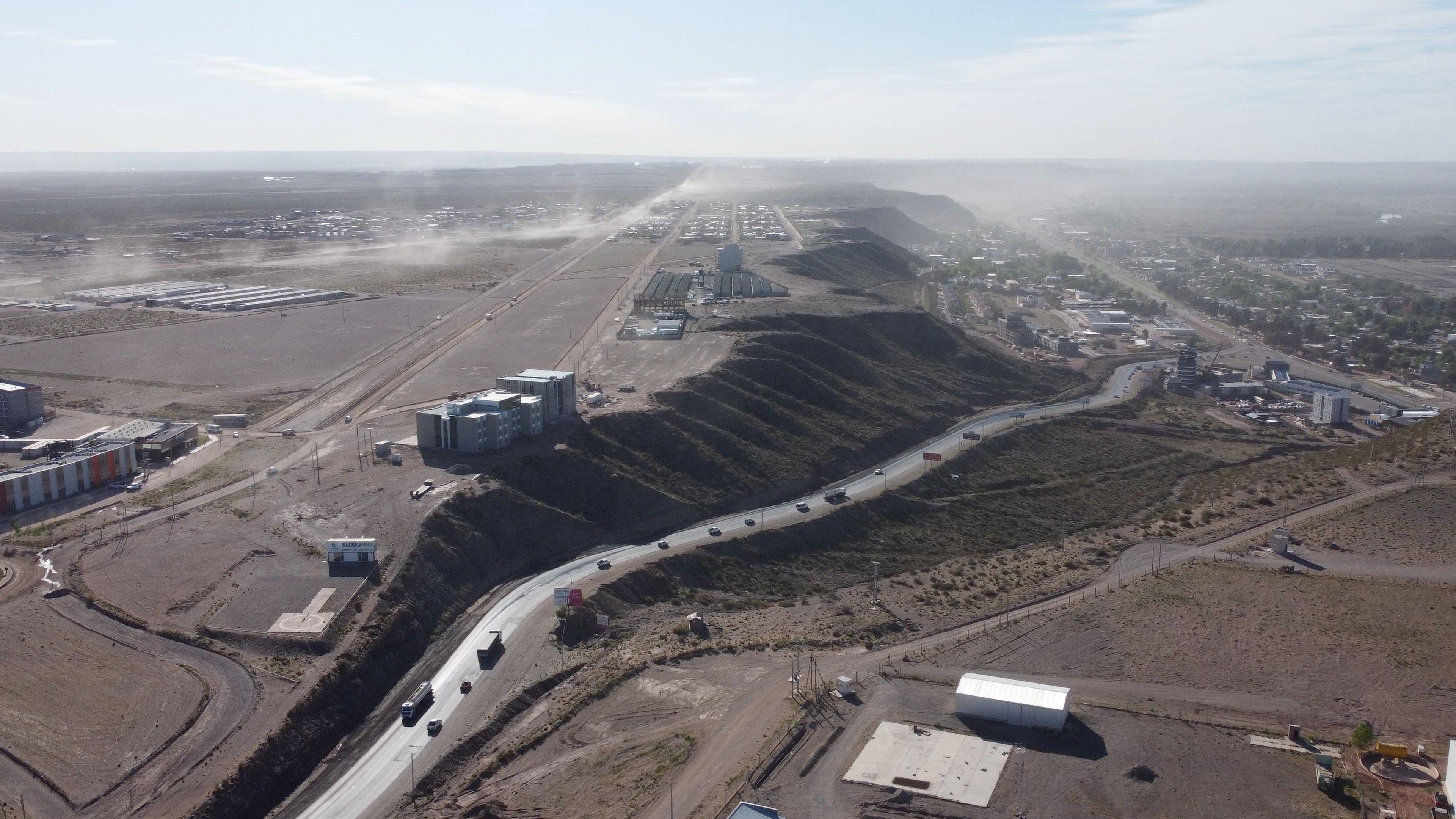 Ruta entre un pueblo con árboles y una meseta árida. 