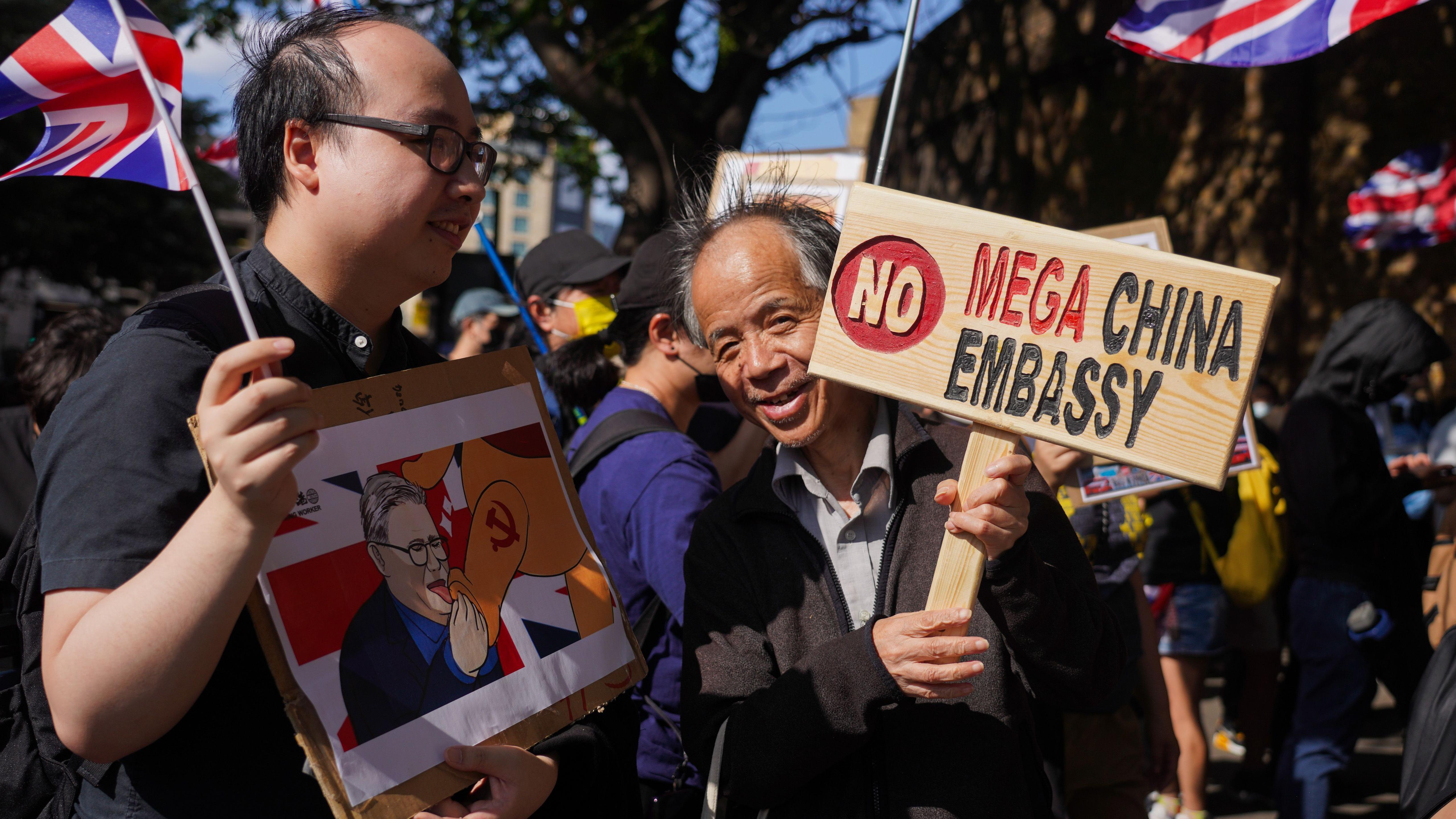倫敦前皇家鑄幣廠外幾位香港移民舉起反對中國「超級大使館」用作監視活動的標語牌（14/6/2025）