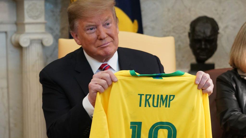 Donald Trump sostiene una camiseta de la selección de Brasil con su apellido