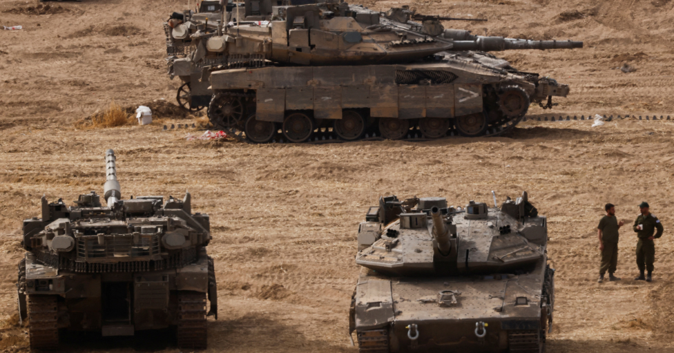 Dos militares israelíes, junto a tres tanques en la frontera entre Israel y Gaza. 