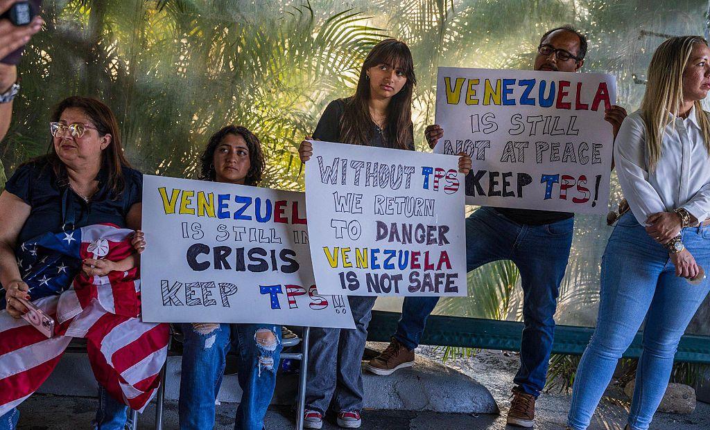 Varias personas sujetan carteles contra la eliminación del TPS.