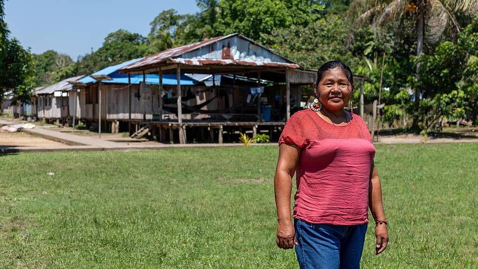 Mari Luz Canaquiri frente a una fila de casas en su comunidad