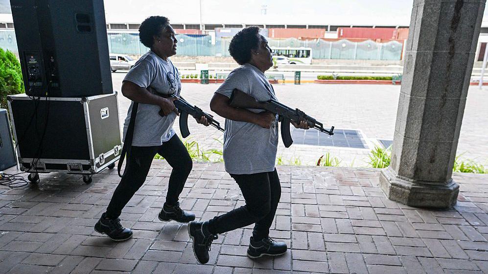 Las hermanas gemelas Carmen y María Santana, miembros de la Milicia Nacional Bolivariana, corren con fusiles en mano durante un ejercicio de entrenamiento militar en La Guaira, Venezuela, el 8 de octubre de 2025.