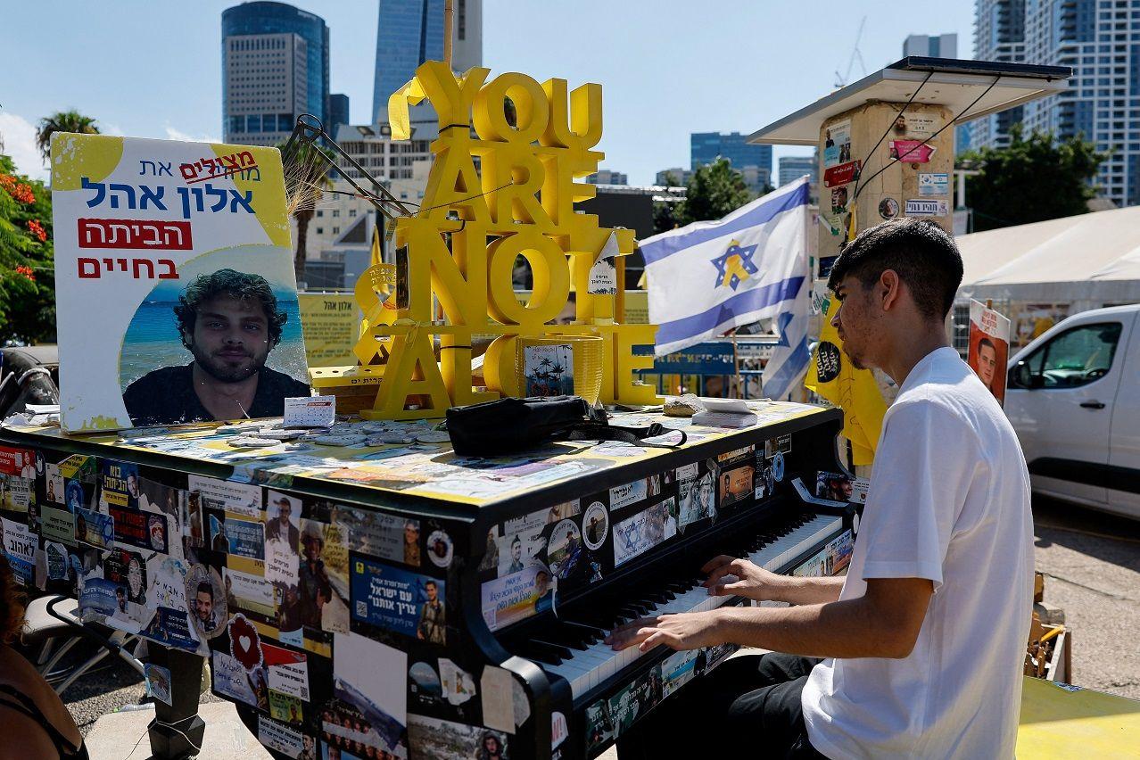 A boy plays the piano at "Hostages Square", after a ceasefire between Israel and Hamas in Gaza went into effect, in Tel Aviv, Israel
