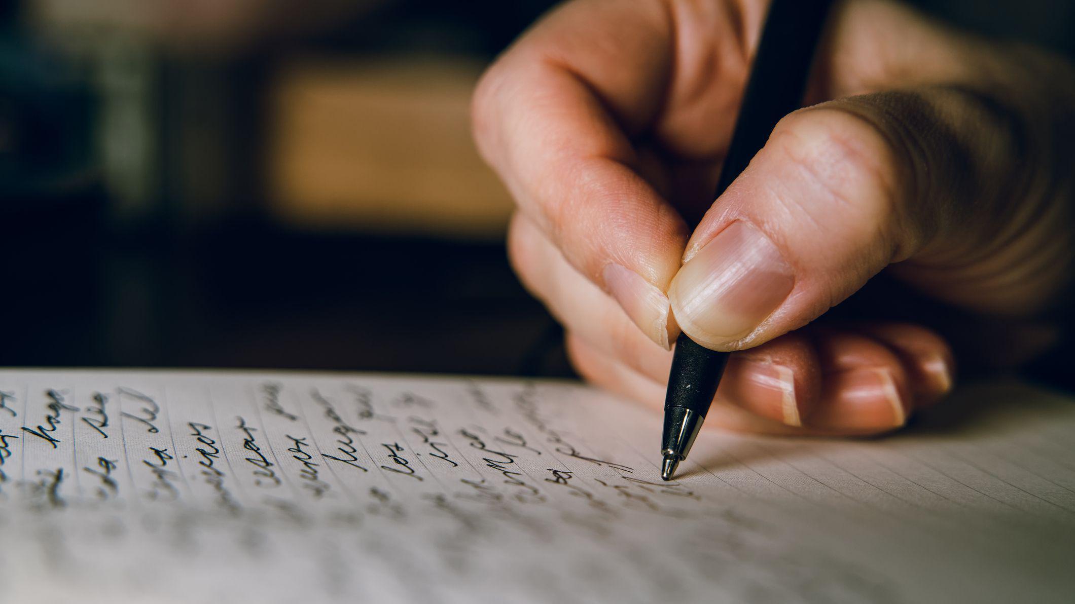M&atilde;o escreve com caneta em um caderno pautado