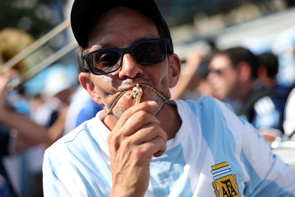 Hombre besa el collar con un dije de la Copa del Mundo de fútbol
