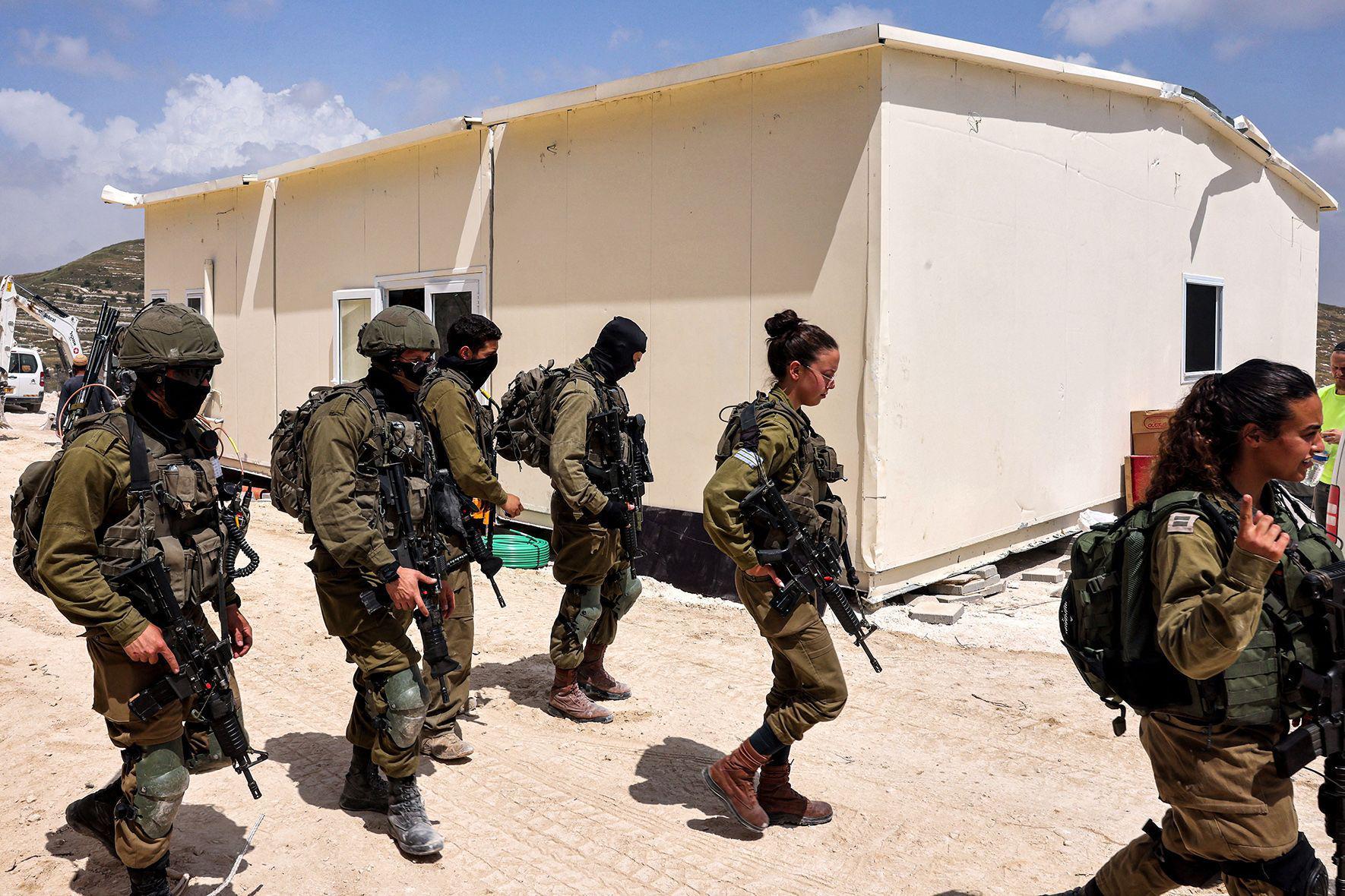 Soldados israelenses caminhando ao lado da construção de um prédio modular em Homesh, na Cisjordânia, em 29 de maio de 2023