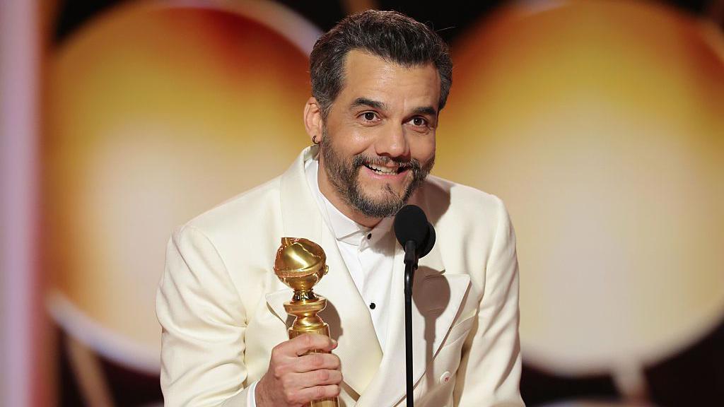 Wagner Moura com uma estatueta na m&atilde;o e falando ao microfone ap&oacute;s ser premiado, na cerim&ocirc;nia do Globo de Ouro, rem 11 de janeiro de 2026.