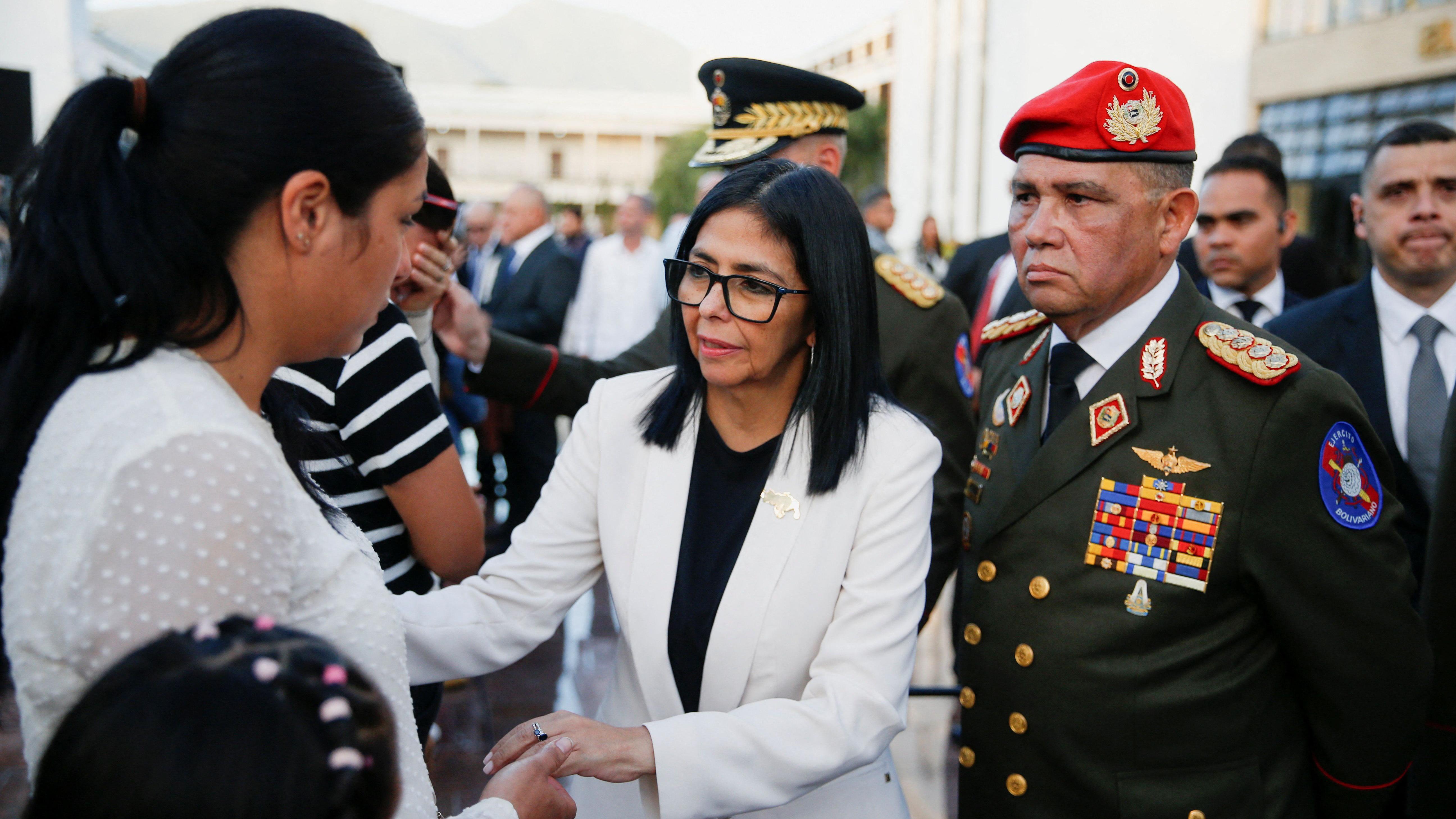 Delcy Rodr&iacute;guez, no centro, sa&uacute;da a esposa e a filha do capit&atilde;o Mois&eacute;s Sequera, &agrave; esquerda, ao lado do general Gustavo Gonz&aacute;lez L&oacute;pez, &agrave; direita, vestido com roupas militares 