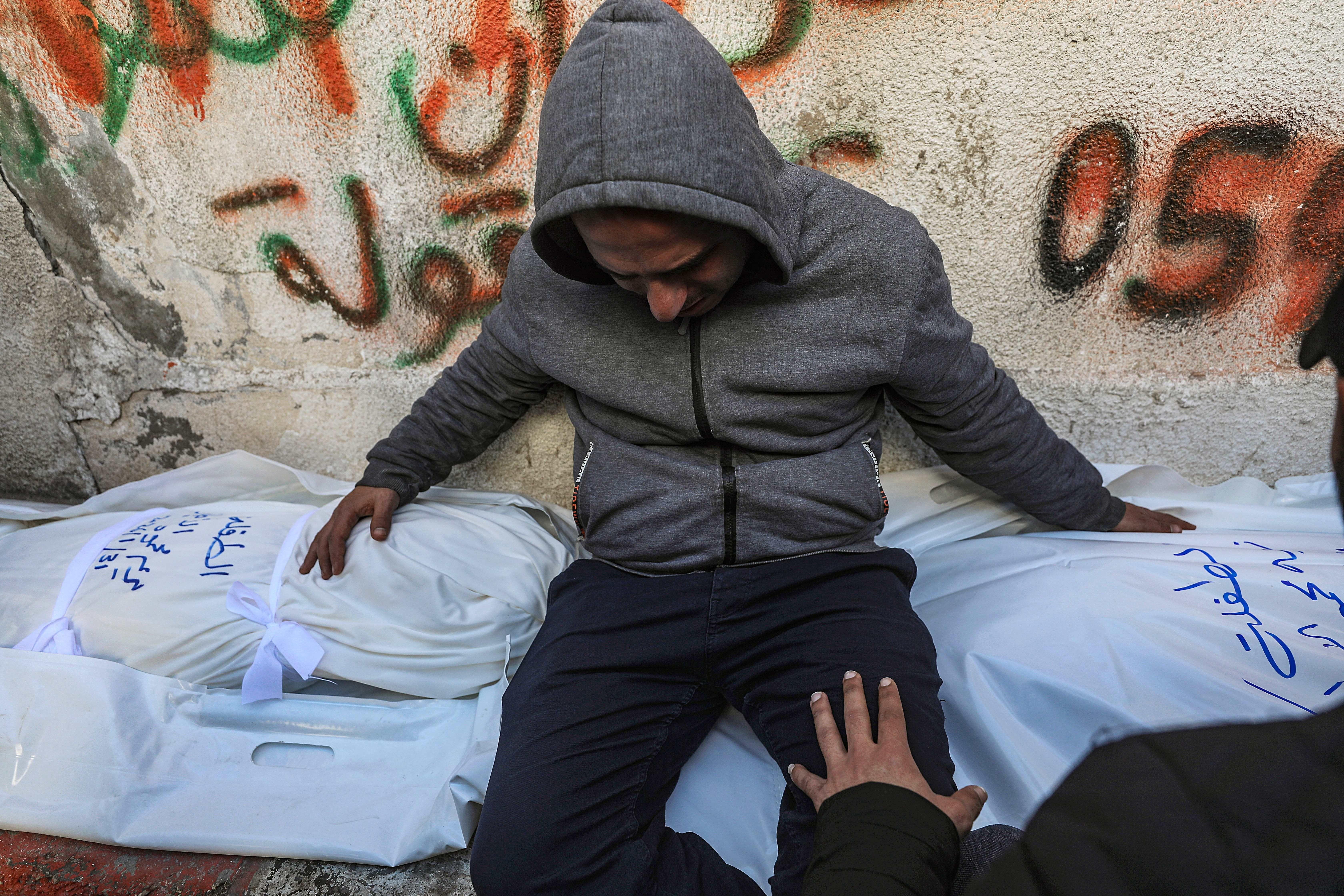 Un hombre llora y abraza dos mortajas.