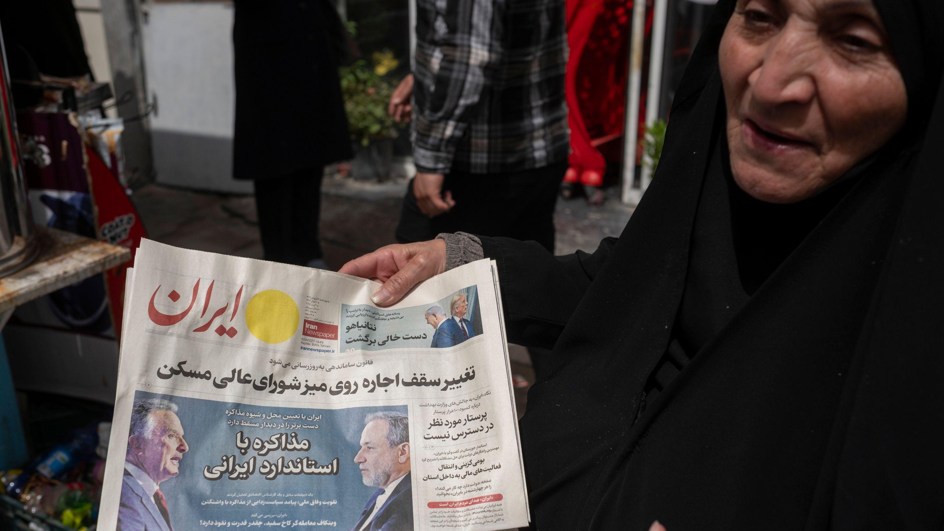 امرأة إيرانية منتقبة تحمل صحيفة عليها صور وزير الخارجية الإيراني عباس عراقجي والمبعوث الخاص للبيت الأبيض ستيف ويتكوف، بينما تعبر عن احتجاجها على المفاوضات بين إيران والولايات المتحدة في وسط مدينة طهران، إيران، في 9 أبريل/نيسان 2025. 