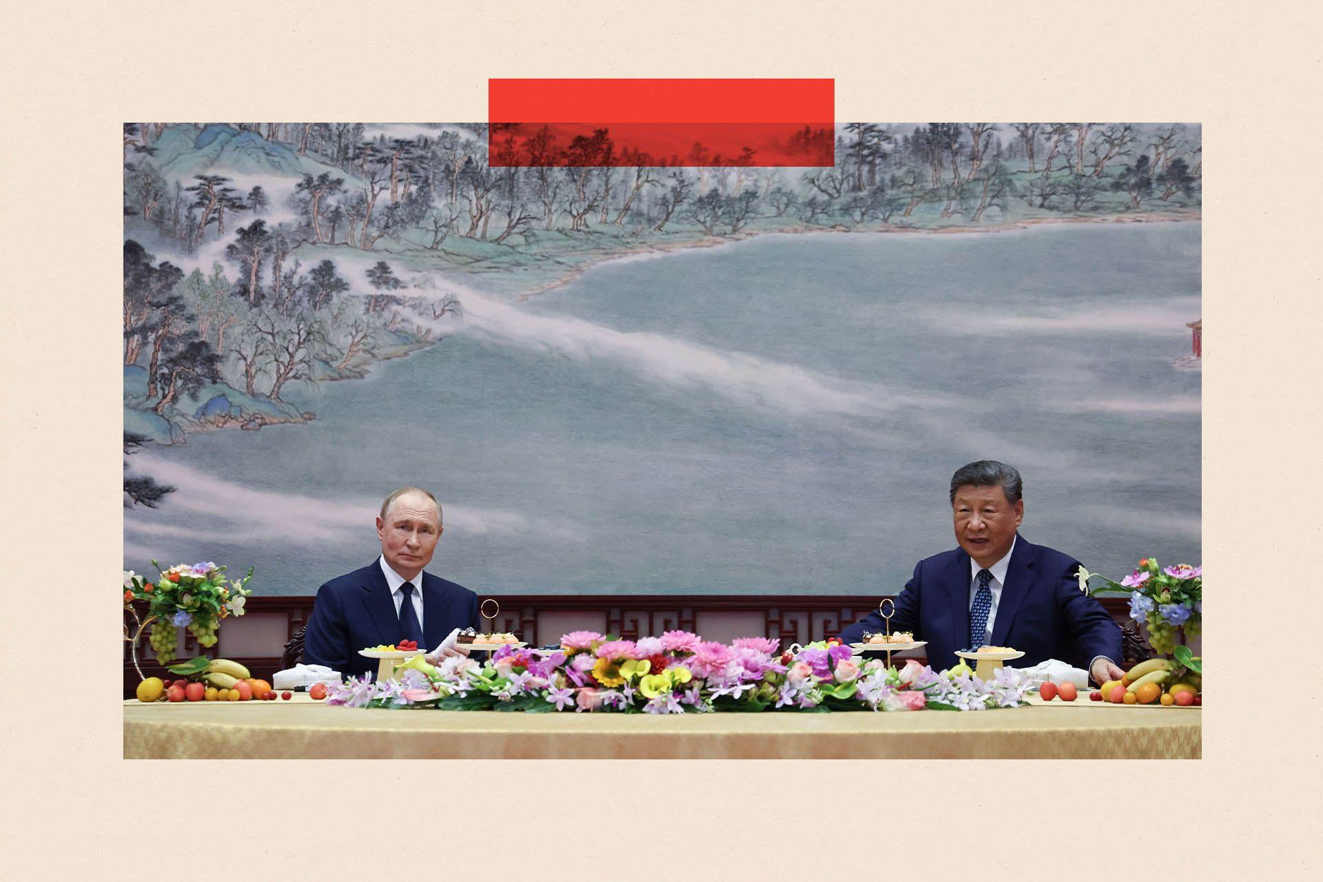 Putin reunido con Xi en Pekín; ambos están sentados frente a una mesa llena de frutas y flores.