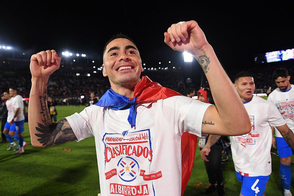 Miguel Almirón con la bandera de Paraguay colgada en el cuello y una camiseta que dice "Clasificados"