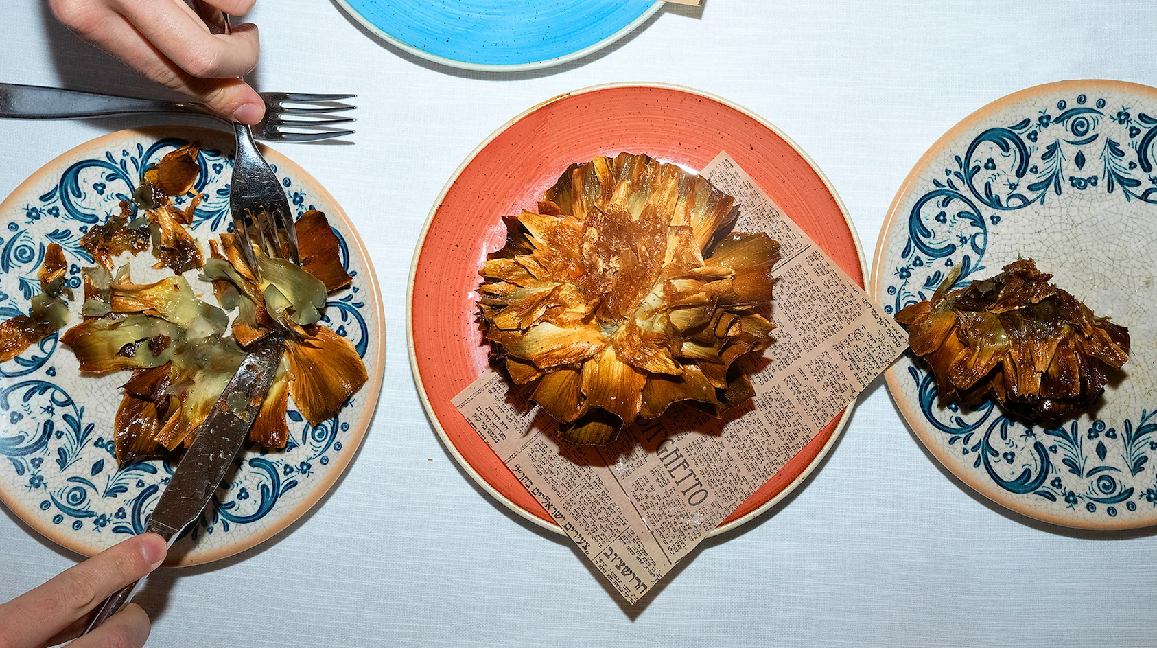 접시 위에 음식이 놓여 있고, 한 사람이 포크와 나이프를 사용하고 있다.