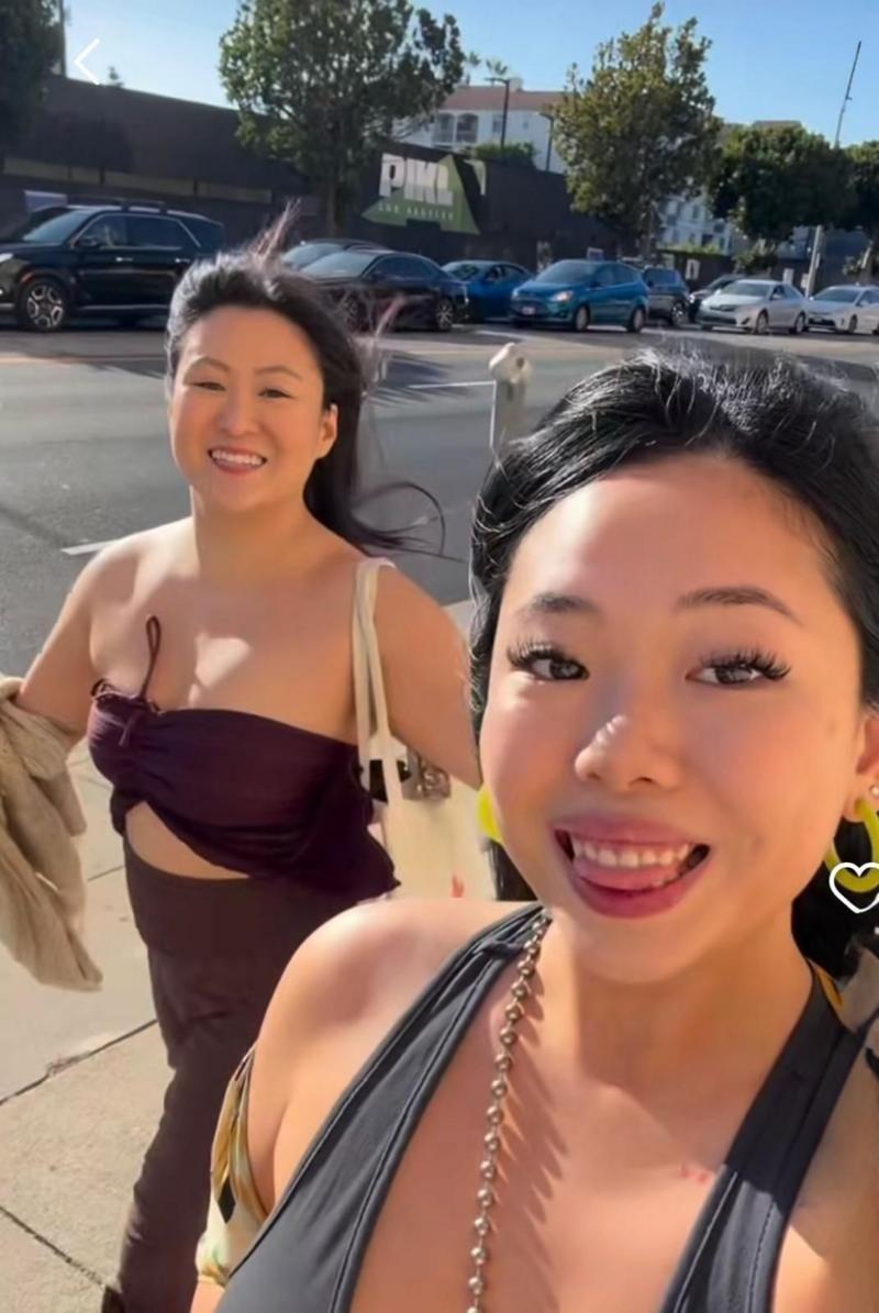 Ambas amigas caminan por una calle con vestidos elegantes y sonriendo a la cámara. 