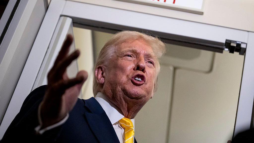 Donald Trump con traje oscuro y corbata amarilla.