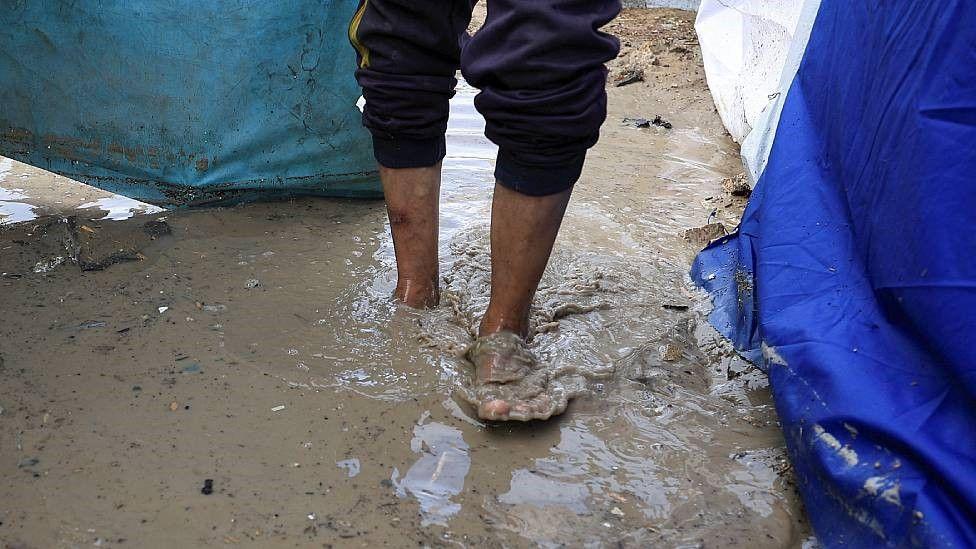Los pies de un hombre caminando con el agua sucia hasta los tobillos