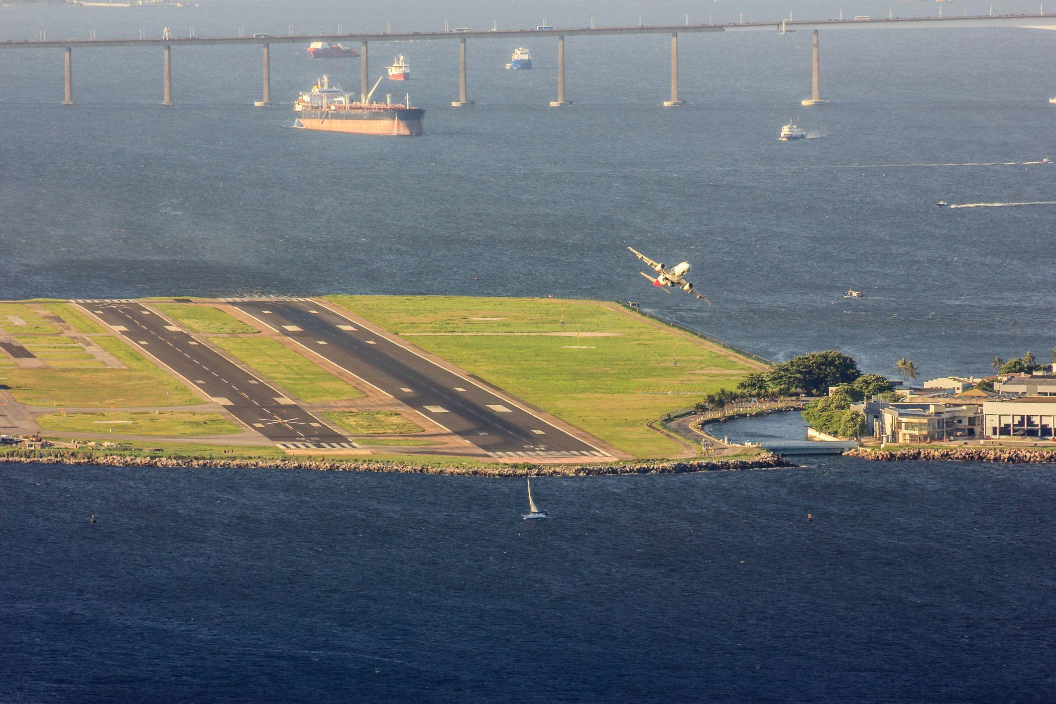 Avião próximo da pista do Santos Dumont, rodeada pela Baía de Guanabara e com a Ponte Rio-Niterói ao fundo