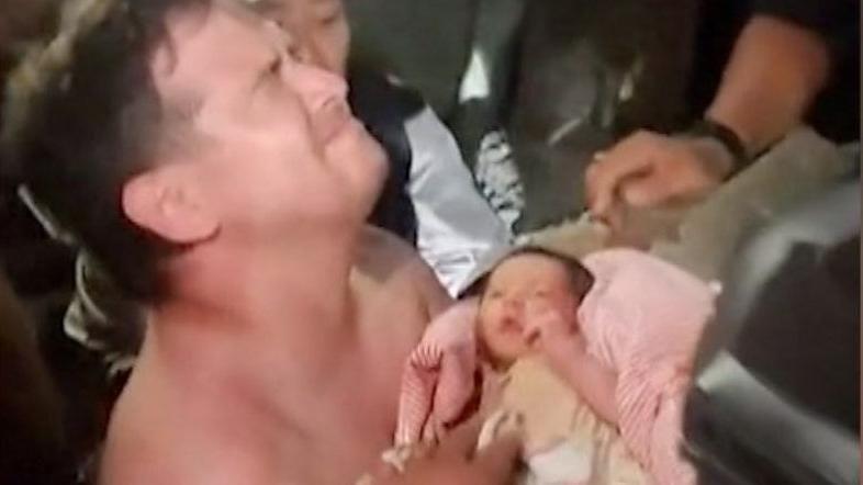 Momento em que o beb&ecirc; &eacute; resgatado e pai o pega no colo
