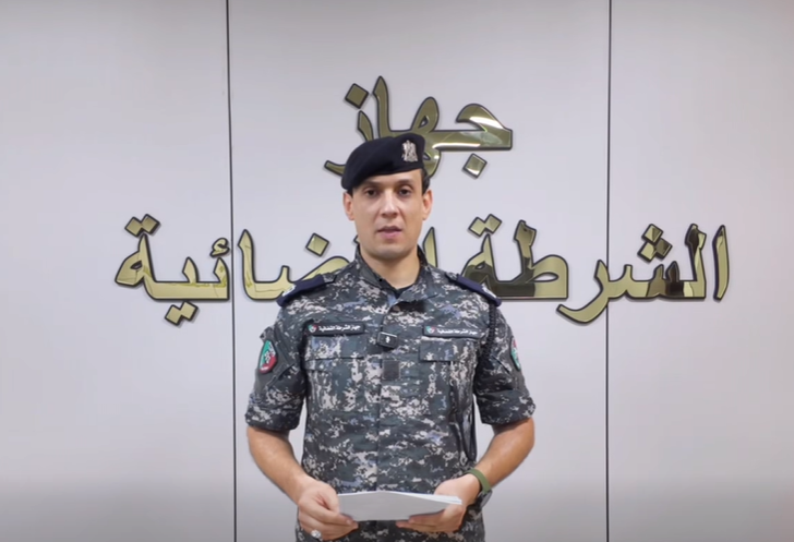يظهر ضابط شرطة مرتدياً الزي الرسمي، وهو يتلو بياناً من ورقة يمسك بها أثناء وقوفه.