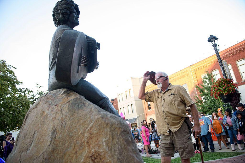 Un hombre se quita el sombrero ante la estatua de Dolly Parton en Tennessee.