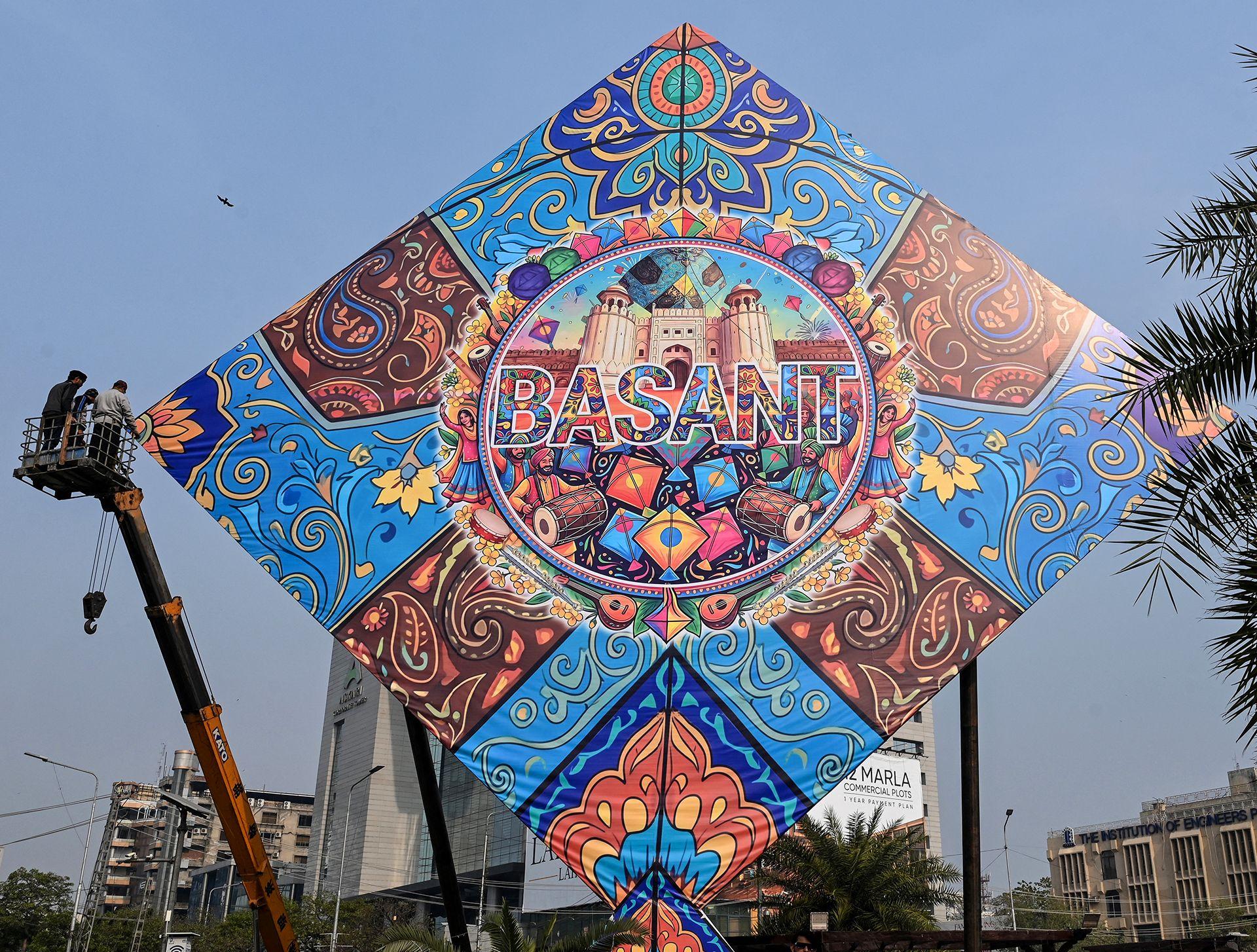 Workers install a large model of a kite celebrating the Basant festival in Lahore on February 3, 2026.