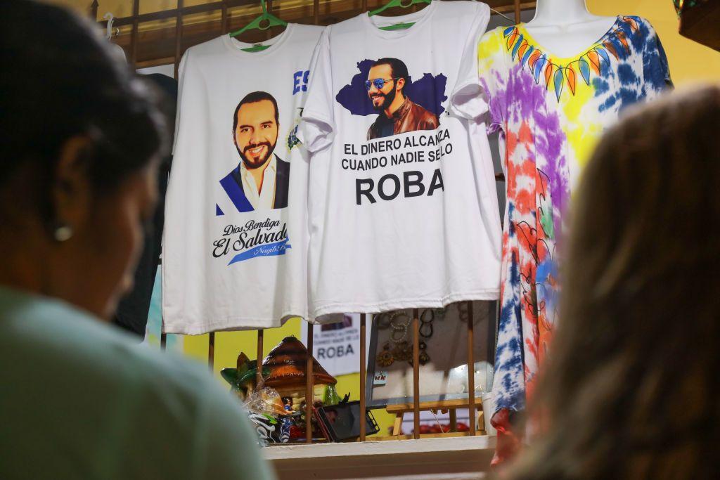 Dos mujeres delante de camisetas con imágenes y frases de Bukele en El Salvador