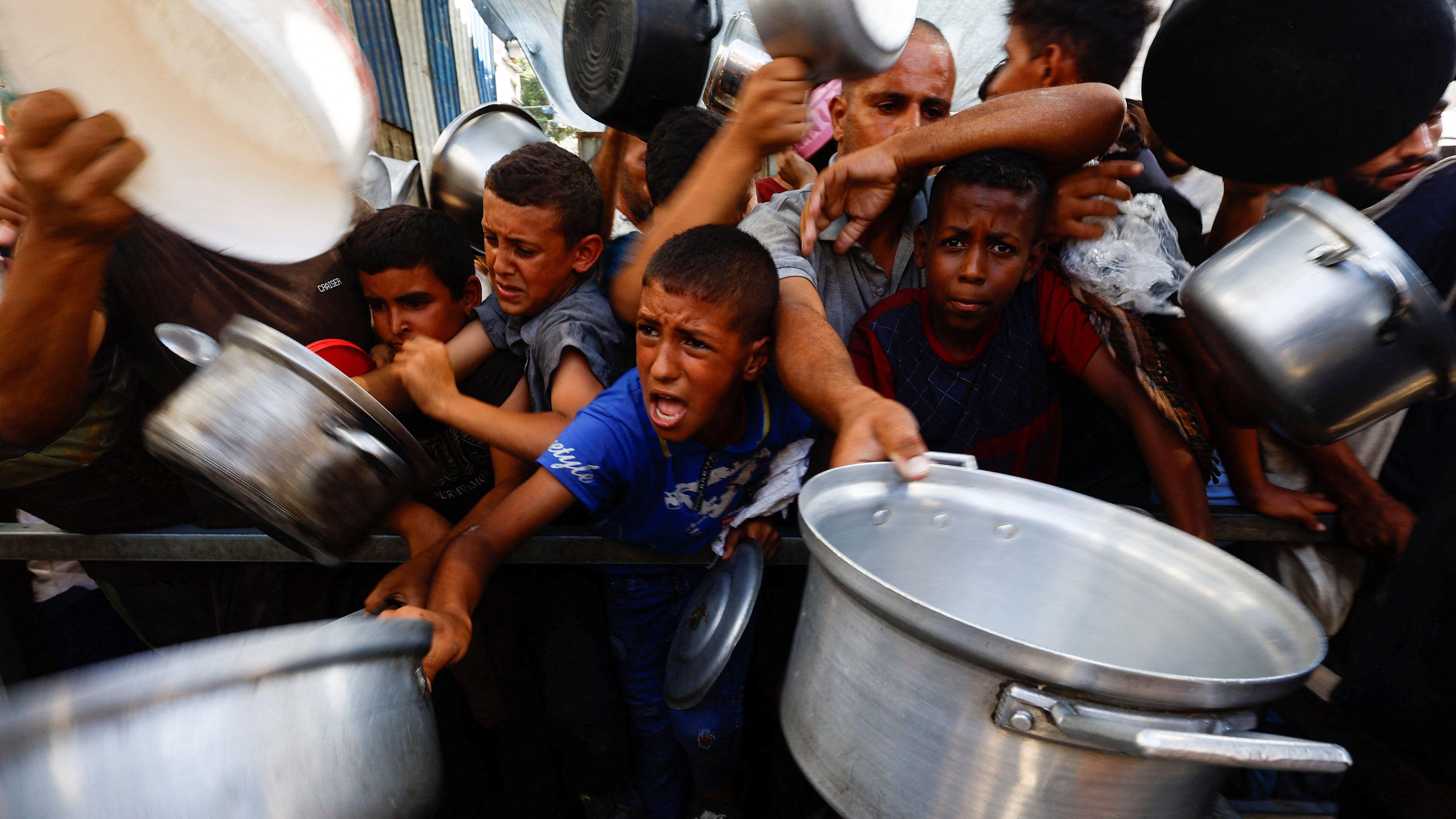 Palestinska deca se tiskaju, pokušavajući da dobiju hranu i pružaju ogromne lonce u centralnom delu Pojasa Gaze