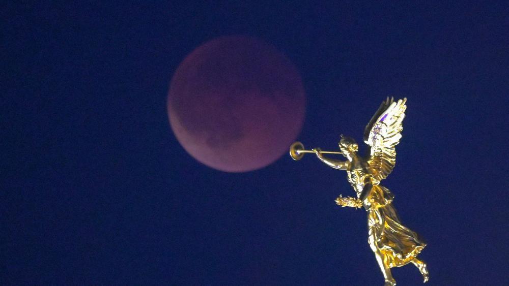 A Lua de Sangue, com uma est&aacute;tua dourada em primeiro plano em Dresden, Alemanha