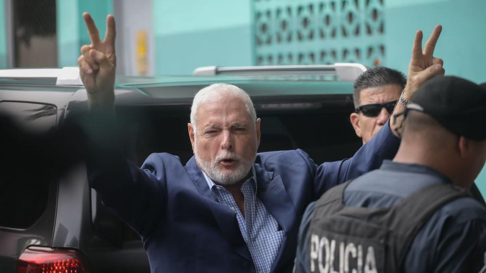 El expresidente Martinelli alza los brazos y hace el signo de la victoria tras salir de un auto en una imagen de archivo.